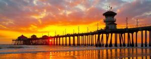 Sunset over a wooden pier at Torrance, CA coast with people walking, reflecting calm seaside vibes.
